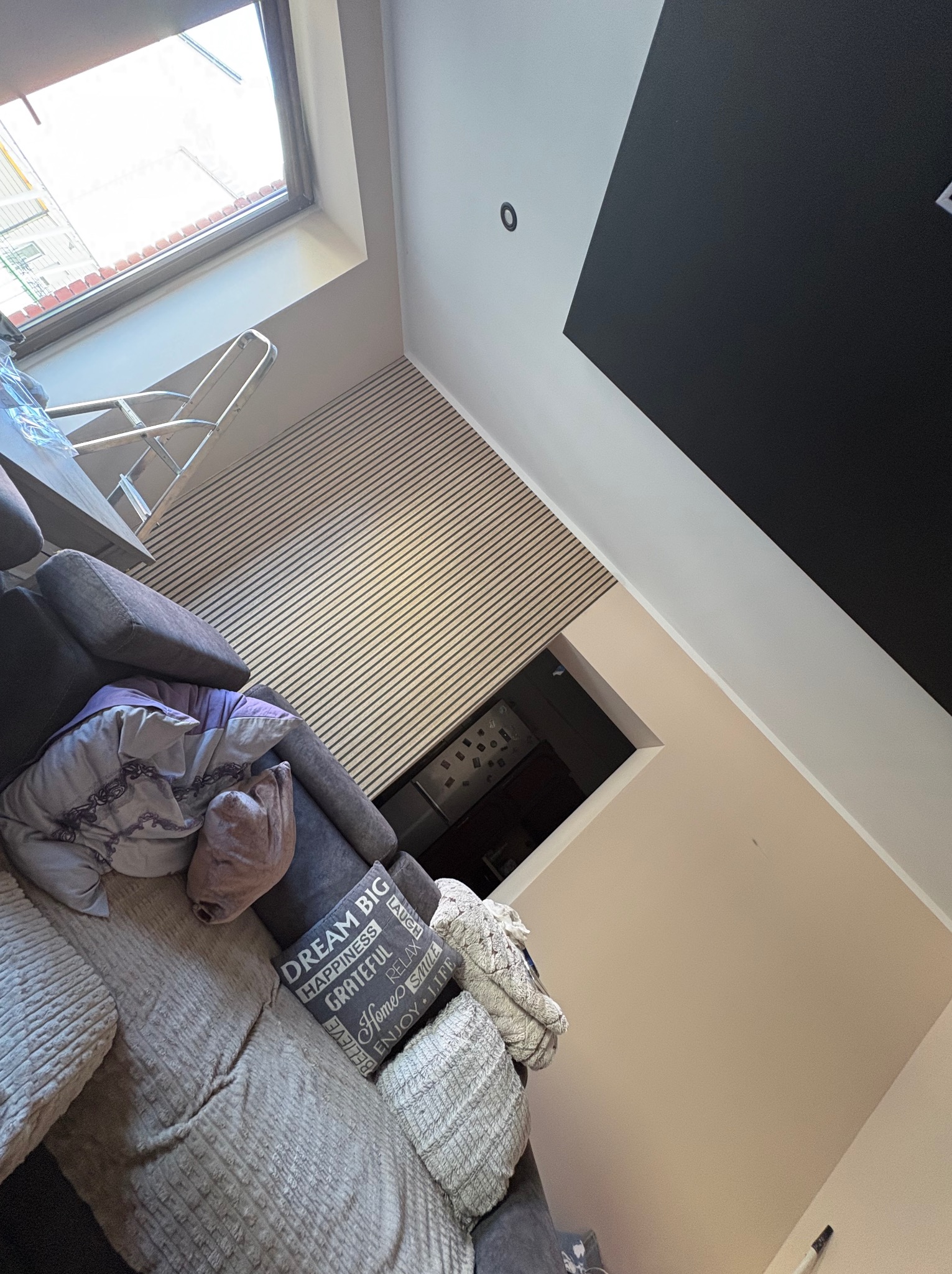 Ukończona ściana z paneli dekoracyjnych w salonie, widok z dołu, z fragmentem sofy i okna dachowego. Nowoczesny design wnętrza z elementami wykończeniowymi.