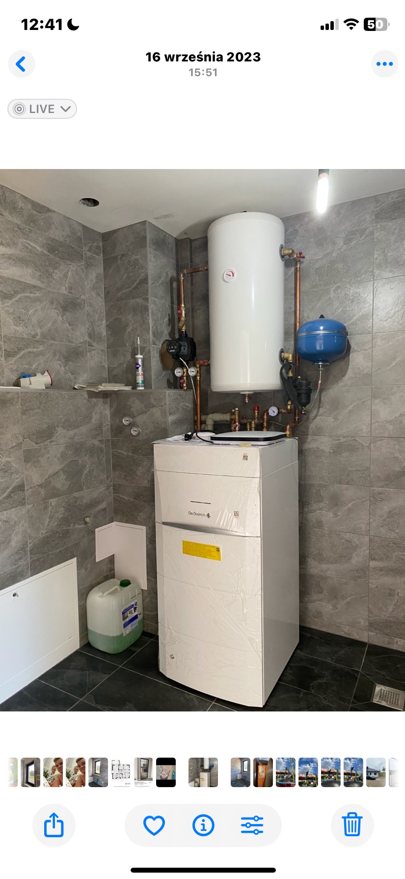 Nowoczesny piec grzewczy De Dietrich z zasobnikiem i osprzętem, zainstalowany w łazience wykończonej szarą płytką imitującą kamień. Częściowo jeszcze w folii ochronnej.