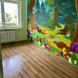 GLAZART - Glazurnictwo Remonty Wykończenia - Pokój dziecięcy z laminowaną podłogą i ścianą ozdobioną malowidłem leśnym z grzybami, kwiatami i motylem. Okno z grzejnikiem po lewej stronie.