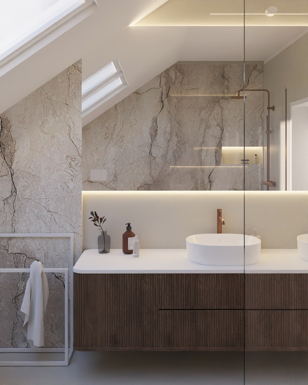 Stylowa łazienka na poddaszu z marmurowymi ścianami, oświetleniem LED i nowoczesną umywalką nablatową. Widoczny fragment kabiny prysznicowej i okno dachowe.