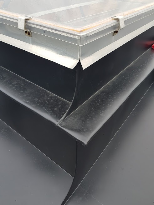 Szczegółowe ujęcie uszczelnienia okna dachowego z czarną, gumową membraną, ukazujące precyzję wykonania i dbałość o detale w izolacji przeciwwodnej.