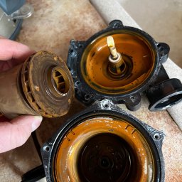 WM POMPY CIEPŁA I KLIMATYZACJA - Zdemontowana, skorodowana pompa obiegowa z widocznym wirnikiem w dłoni, ukazująca zużycie i potrzebę serwisu lub wymiany. Elementy pompy na ceramicznej powierzchni.