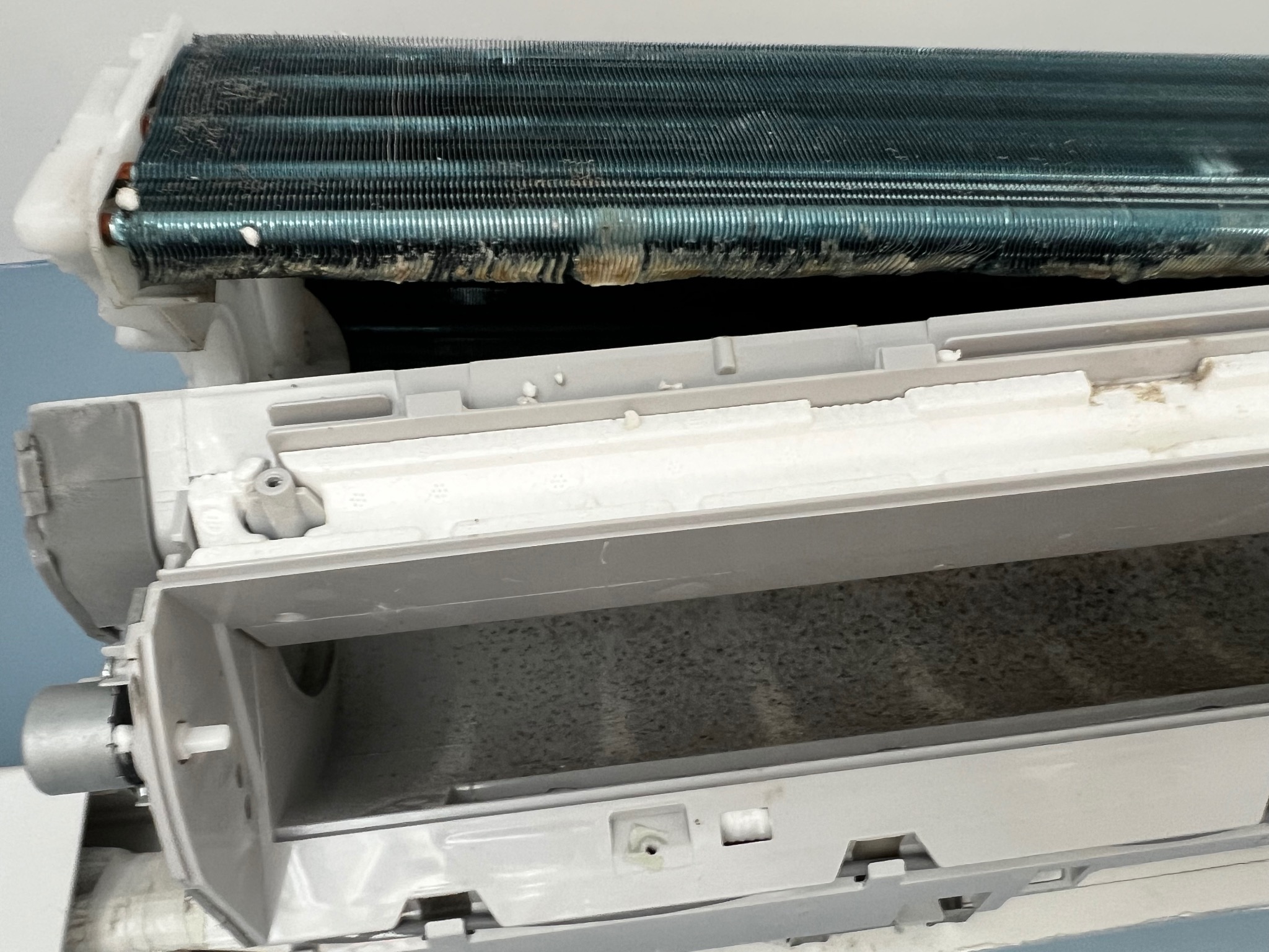 Otwarta, brudna jednostka wewnętrzna klimatyzacji z widocznymi zabrudzeniami na filtrach i lamelach parownika, wymagająca czyszczenia i serwisu.