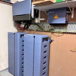 Sun Tech Fotowoltaika Rainczuk Sebastian - Kompletna instalacja magazynu energii Solplanet z falownikiem i modułami bateryjnymi, zamontowana na ścianie z widocznymi przewodami i elementami zabezpieczeń.