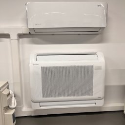 Sun Tech Fotowoltaika Rainczuk Sebastian - Dwa białe klimatyzatory Rotenso zamontowane na ścianie. Górny model ścienny, dolny przypodłogowy z kratką. Widoczne elementy instalacji.