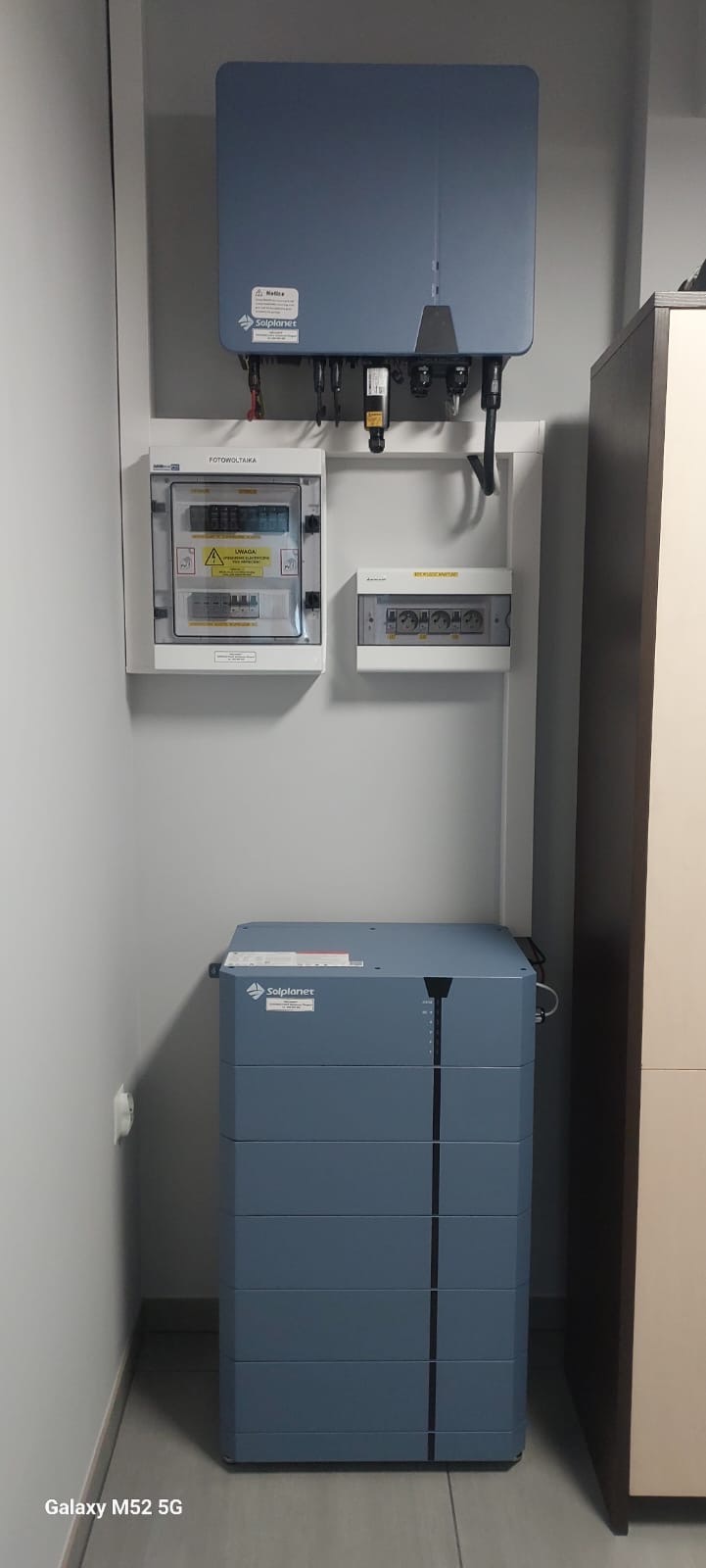 Kompletna instalacja fotowoltaiczna wewnątrz budynku: magazyn energii, inwerter i rozdzielnia elektryczna. Elementy marki Solplanet, schludny montaż.