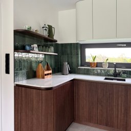 MAR Studio Małgorzata Rembowska - Nowoczesna kuchnia z ciemnozielonymi płytkami i drewnianymi szafkami z ryflowanym frontem. Na blacie marmur, a na półkach i parapecie dekoracje.