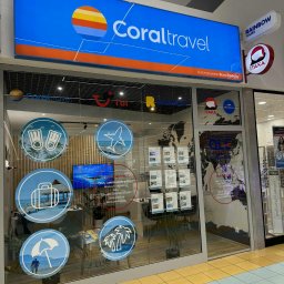 Biuro Podróży Ole Travel - salon podróży - Wejście do biura podróży Coral Travel z logo i naklejkami tematycznymi na szybie, obok loga Itaka i Rainbow Tours. Widoczna mapa świata i oferty wycieczek.