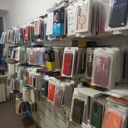 SMARTUP MARCIN GARDOCKI - Ściana z akcesoriami do telefonów: etui w opakowaniach, szkła hartowane. Różne kolory i modele. Widok z dołu, oświetlenie sklepowe.