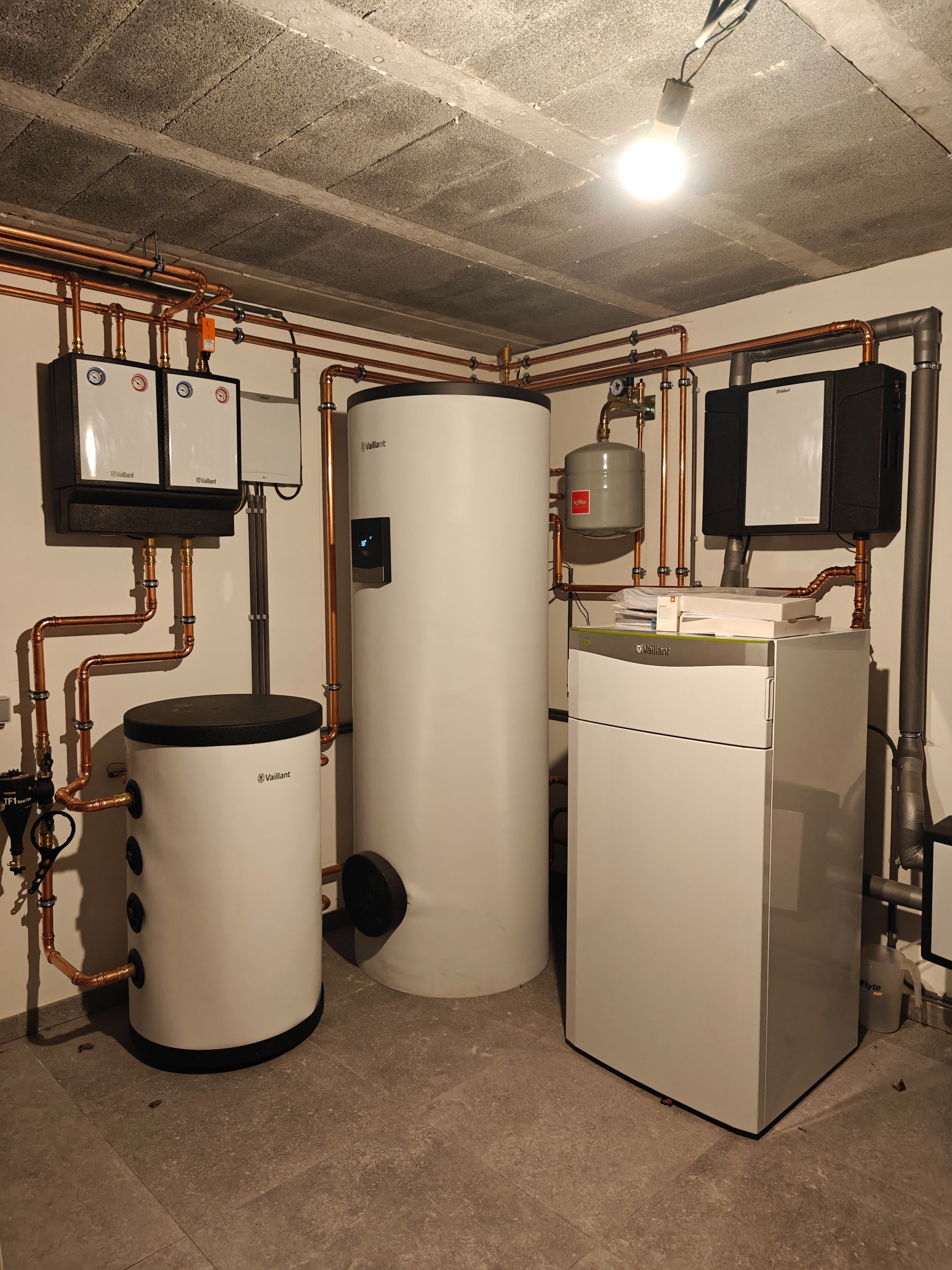 Kompletna instalacja grzewcza Vaillant w kotłowni: piec gazowy, zbiorniki, pompy obiegowe i miedziane rury. Nowoczesny system z elementami sterowania.