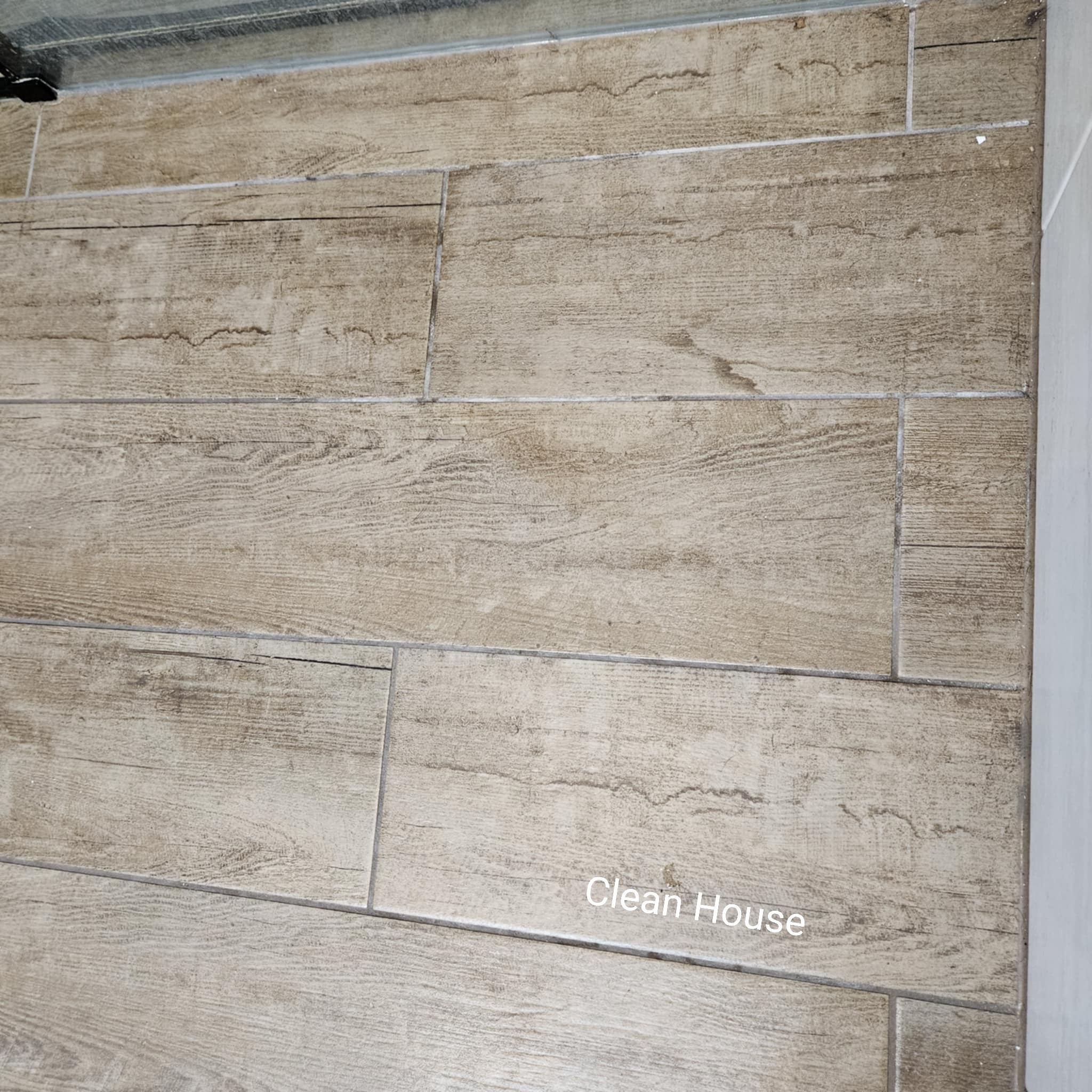 Brudna podłoga z płytek imitujących drewno przed czyszczeniem. Widoczne zabrudzenia w fugach i na powierzchni płytek. Niejednolity kolor, brak połysku.