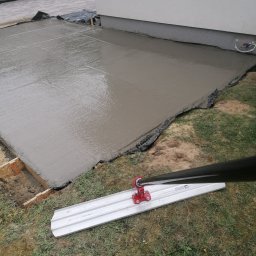 FHU KLAUDIA KŁODA - Wylany, świeży beton na fundamencie z widoczną listwą do rozprowadzania betonu. Widoczne szalunki i folia zabezpieczająca. Prace fundamentowe w toku.