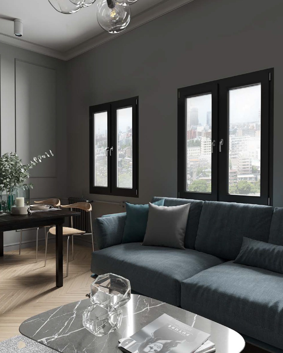 Nowoczesny salon z szarymi ścianami i dwoma oknami z czarnymi ramami, przez które widać panoramę miasta. Na pierwszym planie sofa i stolik kawowy.