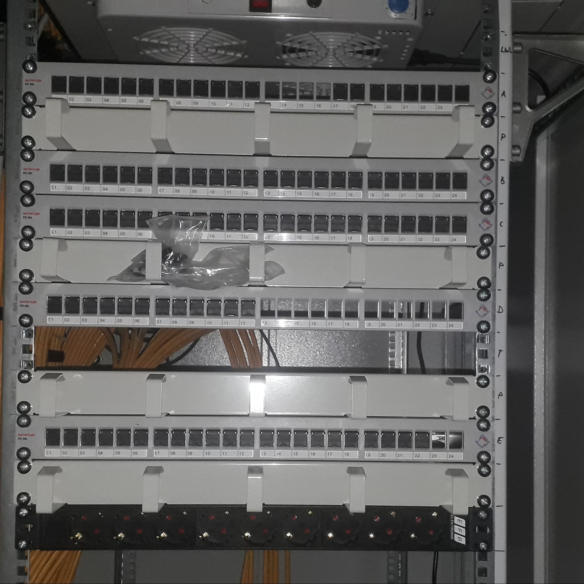 Panel krosowniczy z kablami światłowodowymi w szafie rack. Widoczne porty oznaczone numerami, kable uporządkowane. Element infrastruktury sieciowej.