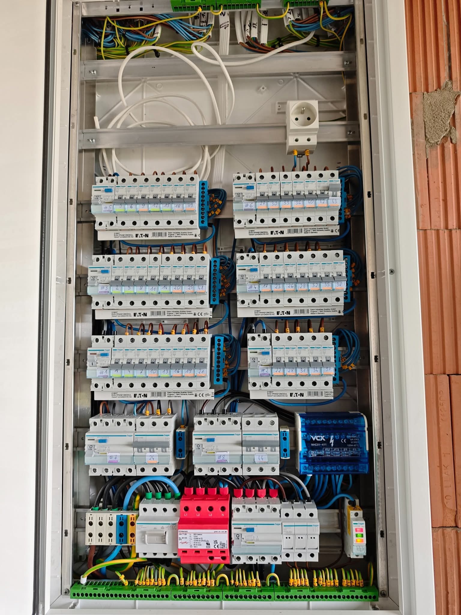 Rozdzielnica elektryczna z zabezpieczeniami różnicowoprądowymi i nadprądowymi marki Eaton, okablowana wewnątrz białej szafki, widok z bliska na instalację.