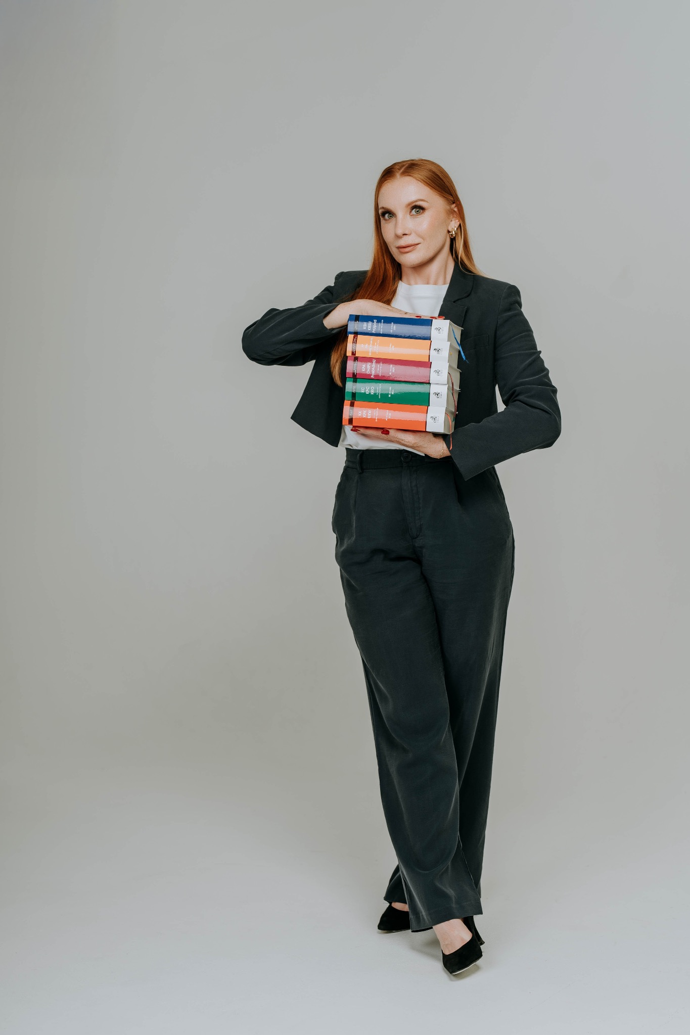 Prawniczka z Zielonej Góry w garniturze trzyma stos kodeksów. Profesjonalizm i wiedza prawna w jednym ujęciu. Kancelaria oferuje szeroki zakres usług.