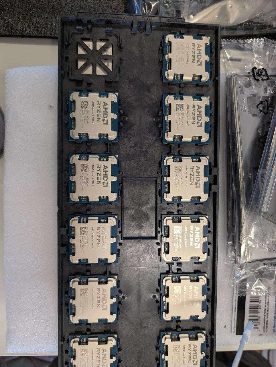 Dziesięć procesorów AMD Ryzen 5 9600X w czarnej, plastikowej wytłoczce, gotowych do instalacji. Widoczne opakowania i akcesoria montażowe w tle.