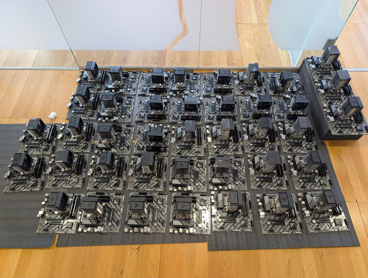 Rząd płyt głównych z procesorami i chłodzeniem, ułożonych na podkładkach, gotowych do instalacji w serwerowni. Widok z góry, oświetlenie naturalne.