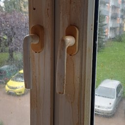 Clean & Care Heroes Marzena Dominik-Kublik - Zabrudzone okno PCV z widocznymi zaciekami i brudem na ramach oraz szybach. Widok na zewnątrz z elementami zieleni i budynków w tle.