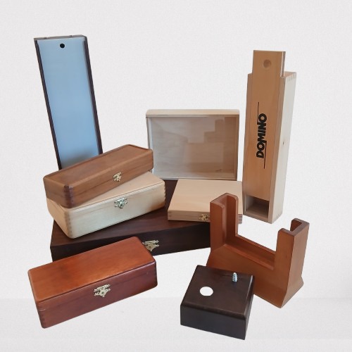 Różnorodne, drewniane opakowania: pudełka z wieczkami, skrzynki z zapięciami, stojak i podstawa. Część z nich jest surowa, a część wykończona bejcą w różnych odcieniach brązu.