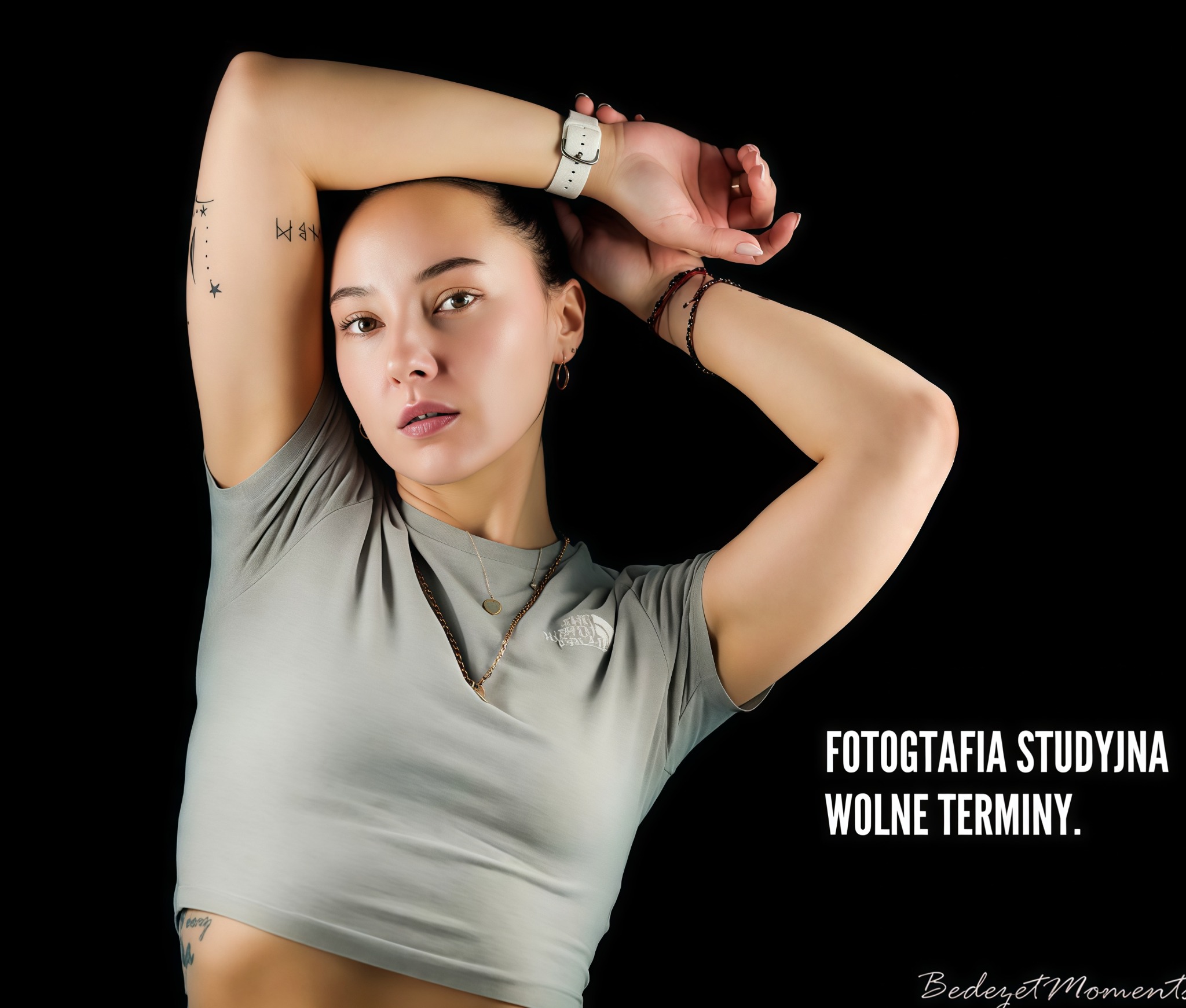 Portret kobiety w studio na czarnym tle, z tatuażami na ramieniu i delikatną biżuterią. Widoczny napis 'Fotografia studyjna, wolne terminy'.