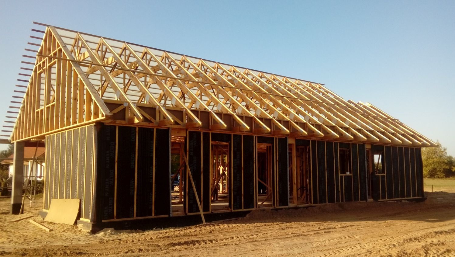 Konstrukcja domu w budowie w Inowrocławiu: drewniany szkielet z czarną membraną, widoczne krokwie dachu, przygotowany do dalszych prac wykończeniowych.