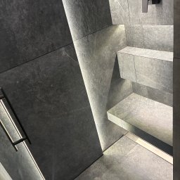 Ivan Vovk - Nowoczesna kabina prysznicowa z szarych płytek imitujących kamień, z podświetleniem LED wzdłuż krawędzi i czarną armaturą. Minimalistyczny design.