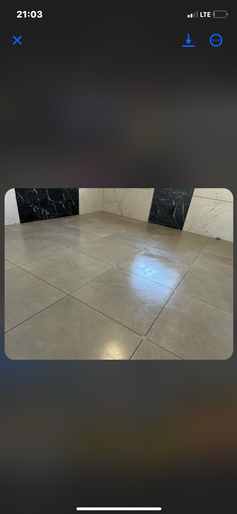 Wykończona podłoga z płytek w odcieniach beżu, z fragmentem ściany wyłożonej czarno-białymi płytkami imitującymi marmur. Widok na narożnik pomieszczenia.