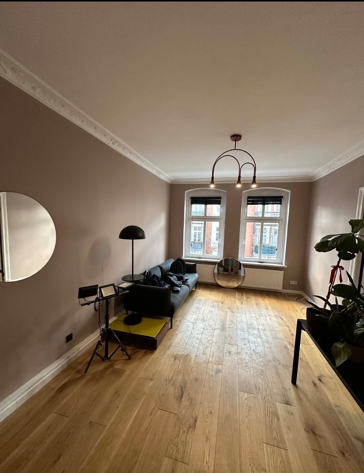 Pokój po odświeżeniu ścian w Mosinie. Jasne, drewniane podłogi, ściany w odcieniach beżu, nowoczesne oświetlenie i dekoracyjne listwy przysufitowe.