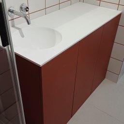 ZPHU Budziński&Motyka s.c. - Nowoczesna szafka łazienkowa z umywalką w kolorze terakoty, biały blat, chromowana bateria, płytki na ścianie z brązową fugą. Minimalistyczny design.