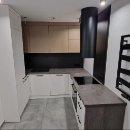 EA studio - Nowoczesna kuchnia w kształcie litery L z białymi i beżowymi szafkami, czarnym okapem i grzejnikiem drabinkowym. Na ścianie grafiki z motywem kawy.