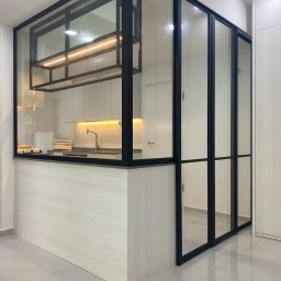 Dmytro Marienko - Nowoczesna, przeszklona konstrukcja z czarnymi profilami oddzielająca kuchnię, z widocznym oświetleniem LED i blatem. Minimalistyczny design, jasne wnętrze.