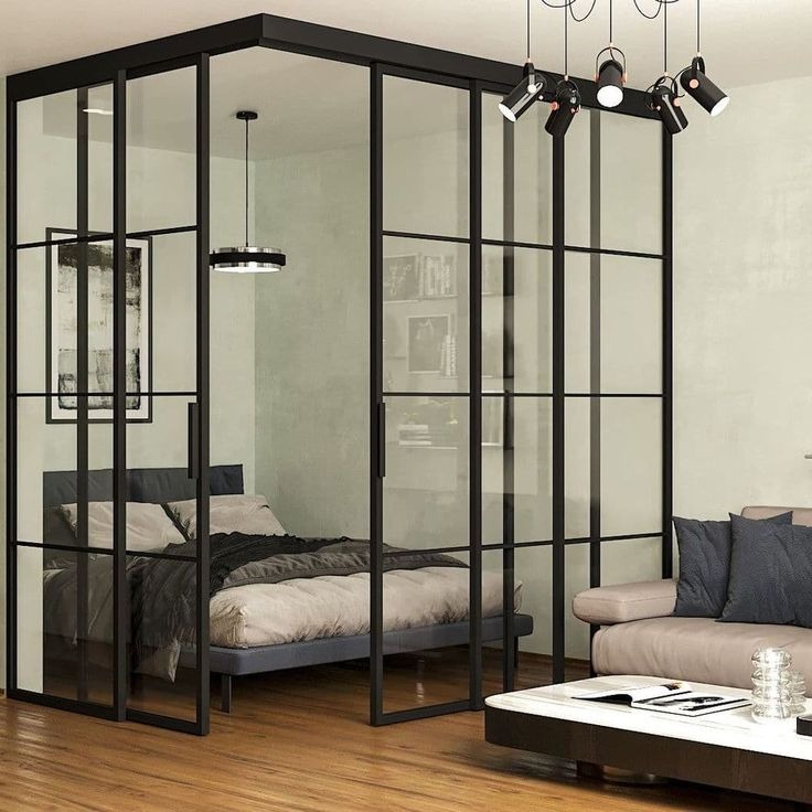 Loftowa ścianka działowa z czarnymi profilami i przeszkleniami oddziela sypialnię od salonu. Nowoczesny design z widocznym oświetleniem punktowym.