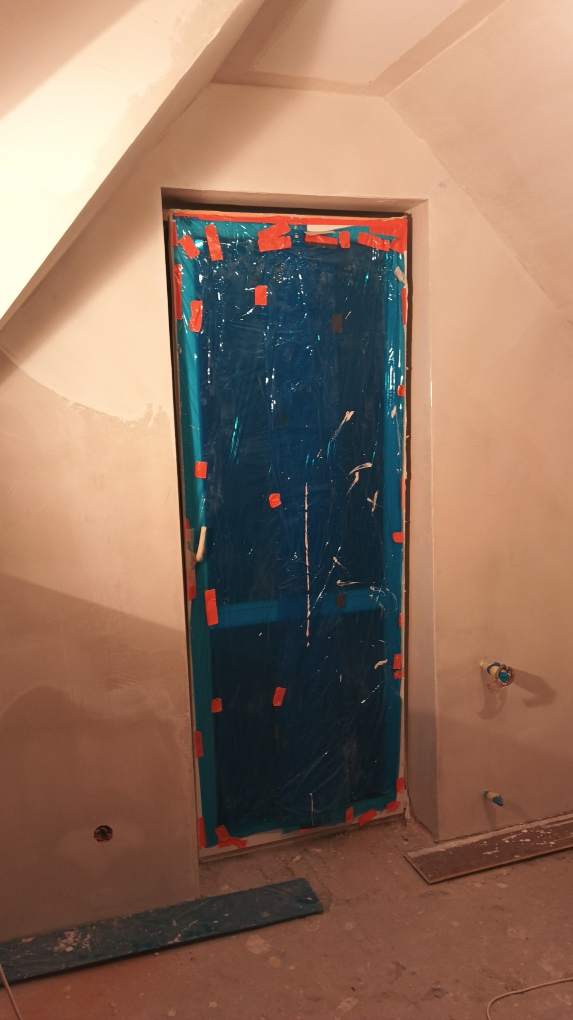 Przygotowanie do malowania w Gdowie: drzwi zabezpieczone folią i taśmą malarską, ściany po szpachlowaniu, gotowe do nałożenia farby.