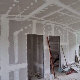 ML-System Marcin Langier - Płyty karton-gips na ścianach i suficie w trakcie montażu, widoczne łączenia. Prace wykończeniowe w Wodzisławiu. Widok na okno i drzwi.