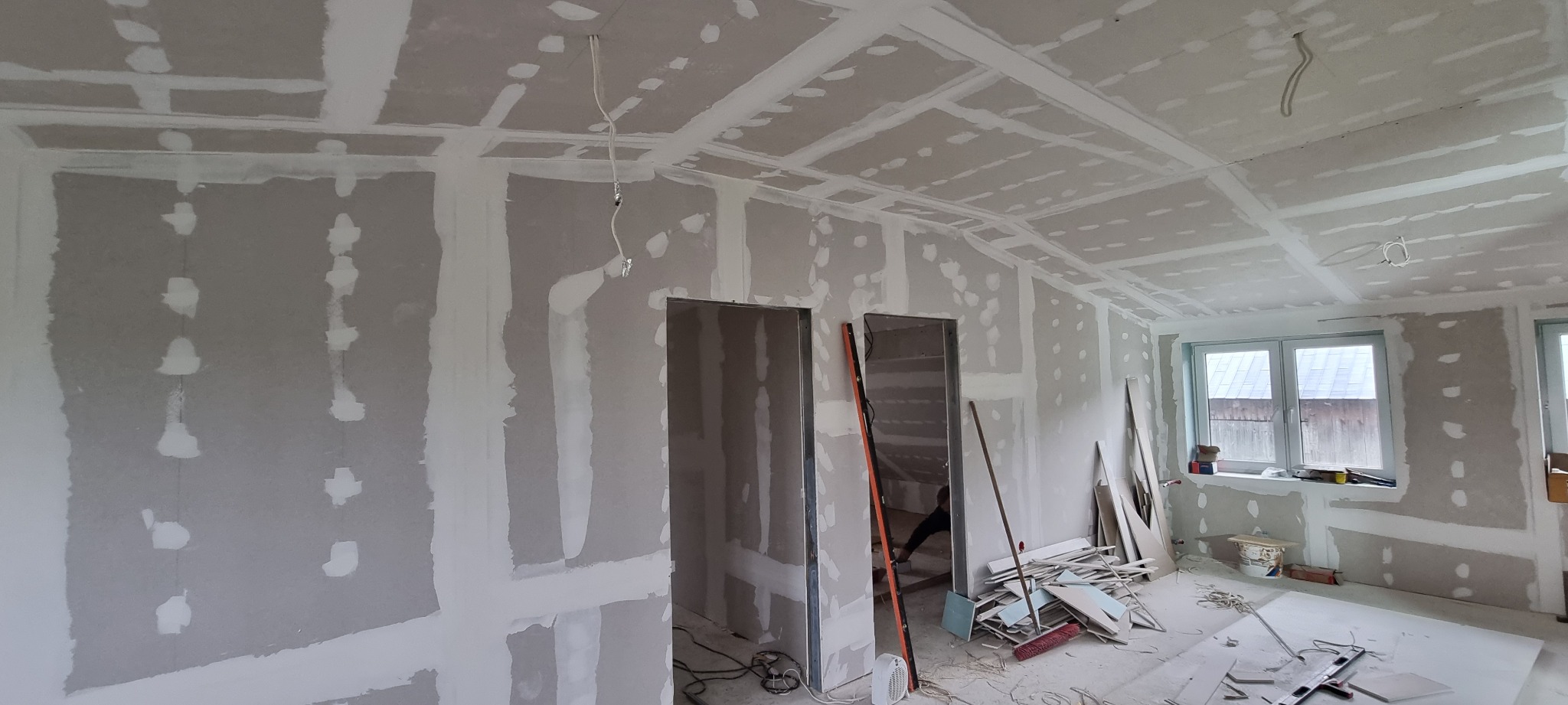 Płyty karton-gips na ścianach i suficie w trakcie montażu, widoczne łączenia. Prace wykończeniowe w Wodzisławiu. Widok na okno i drzwi.