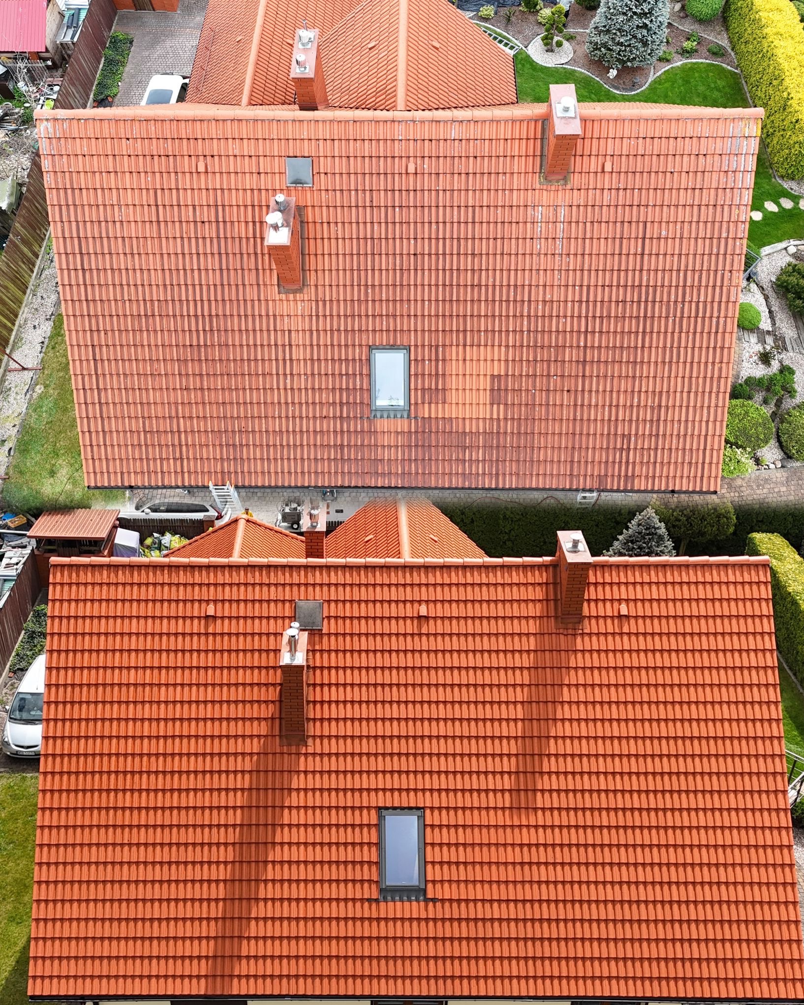 Zdjęcie dachu z dachówki ceramicznej przed i po czyszczeniu, widok z góry. Górna część dachu jest brudna, dolna czysta, ukazując efekt mycia.