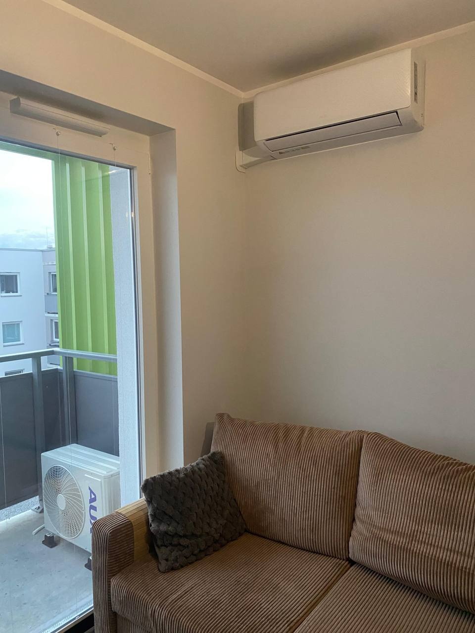 Klimatyzator ścienny w jasnym salonie z balkonem w Siechnicach. Widoczny jednostka wewnętrzna i zewnętrzna. Nowoczesny design, komfort termiczny w mieszkaniu.