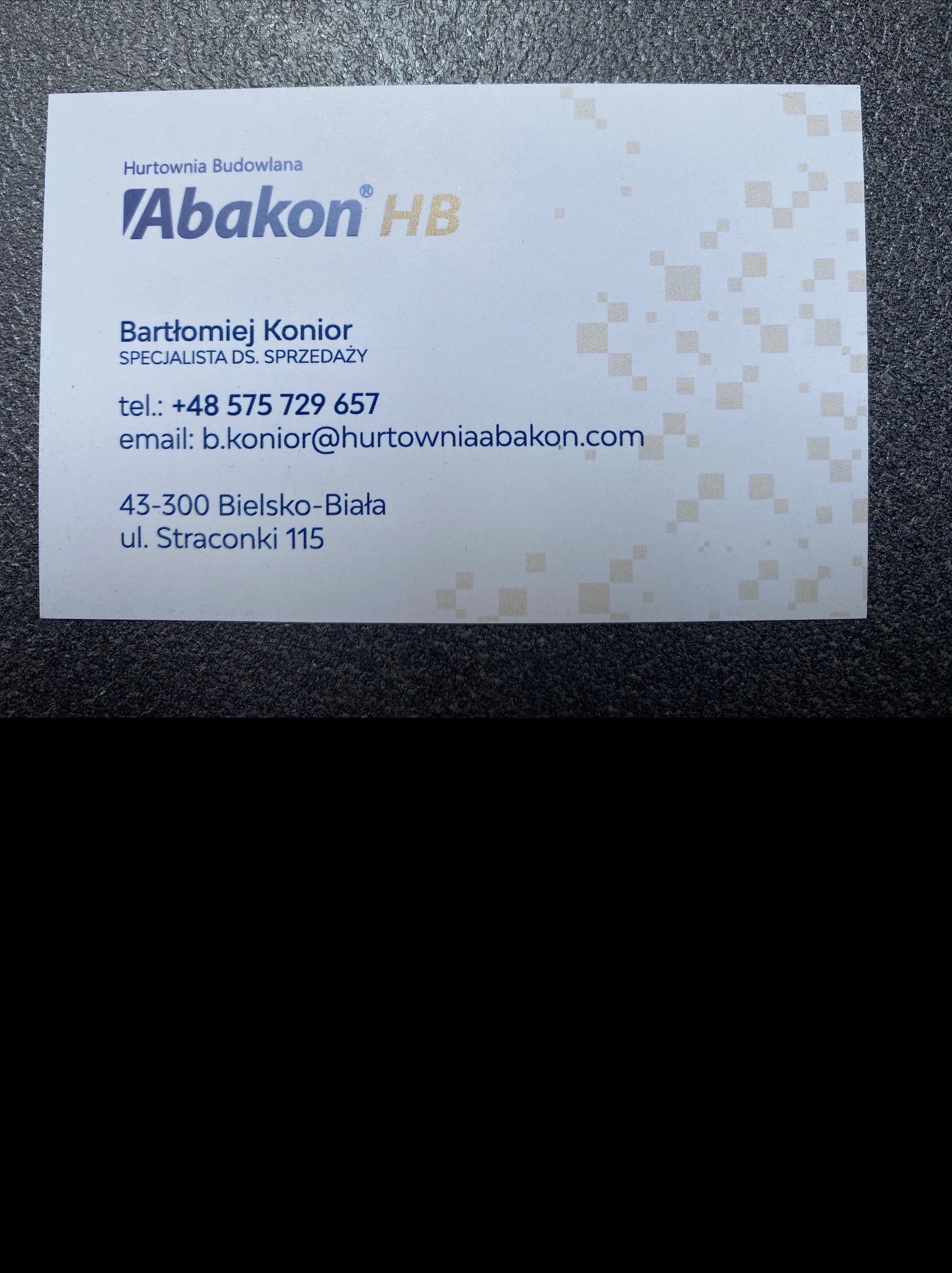 Wizytówka Hurtowni Budowlanej Abakon HB z Bielska-Białej. Dane kontaktowe: Bartłomiej Konior, telefon, email, adres. Tło wizytówki zdobione subtelnym wzorem.