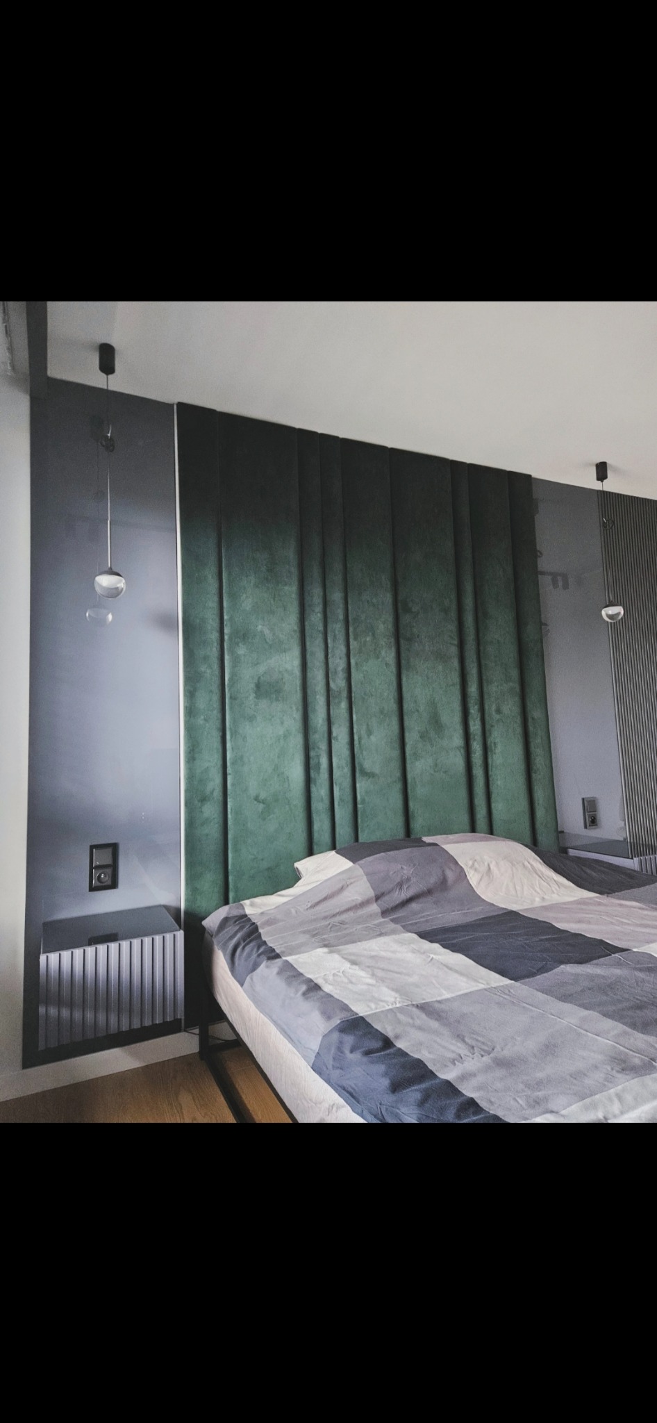 Nowoczesna sypialnia z łóżkiem i wezgłowiem z zielonego weluru. Obok szafka nocna z ryflowanym frontem i lampka wisząca. Minimalistyczny design.