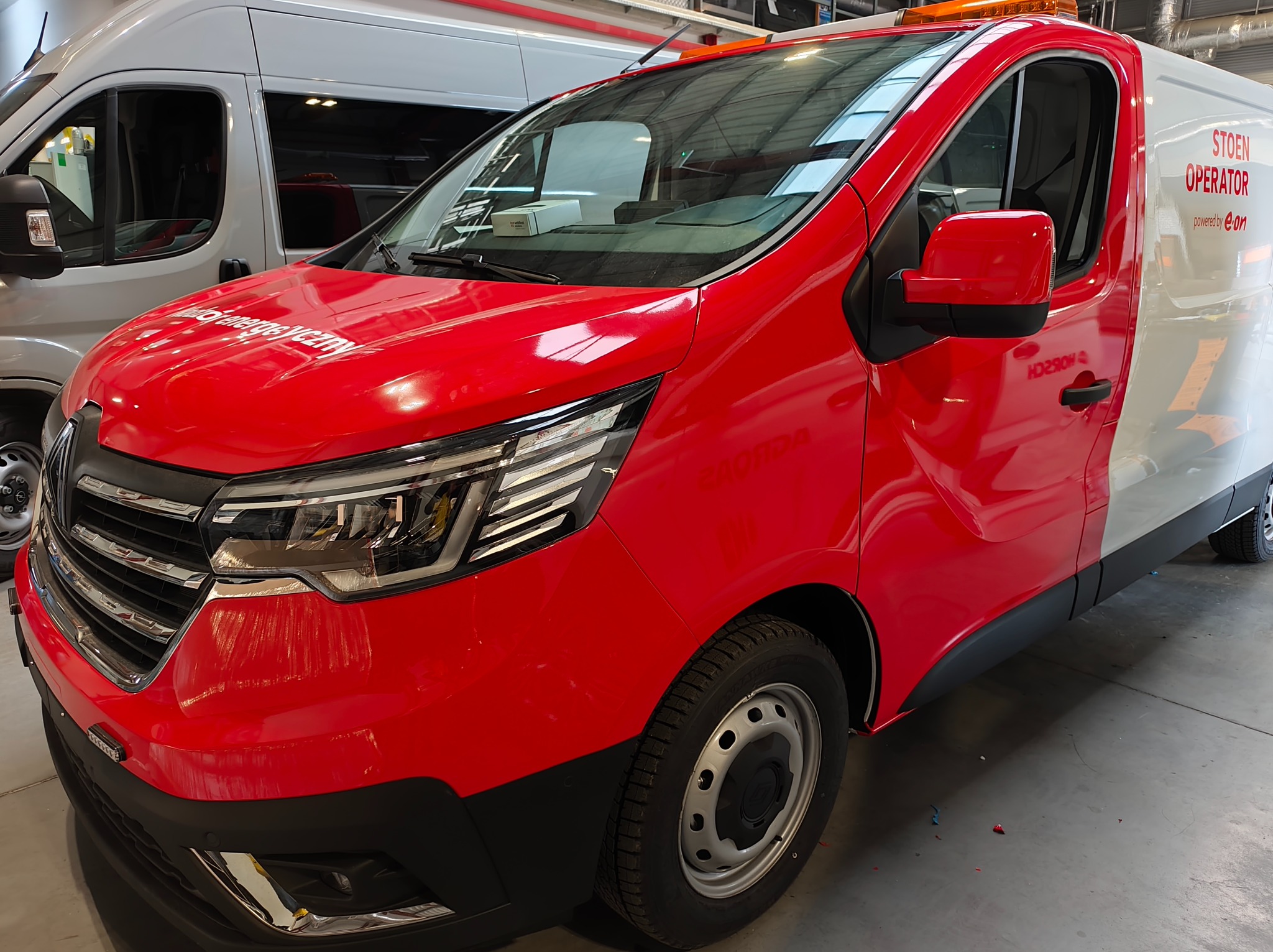 Czerwono-biały van z logo firmy energetycznej, widok z przodu, oświetlenie studyjne, czyste tło. Detal: napis na karoserii.