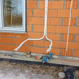 IK Klimat Ivan Ivanieiev - Montaż instalacji freonowej klimatyzacji na ceglanej ścianie budynku w trakcie budowy. Widoczne narzędzia i materiały instalacyjne.