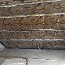 Usługi Ogólnobudowlane Sebastian Chyrzyński - Poddasze z widoczną folią paroizolacyjną Isover, przygotowane do dalszych prac wykończeniowych. Widoczne elementy konstrukcyjne i materiały budowlane.