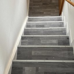 Usługi Ogólnobudowlane Sebastian Chyrzyński - Schody wyłożone panelami w odcieniach szarości z metalowymi listwami, widok z góry. Realizacja z Dębnicy Kaszubskiej.