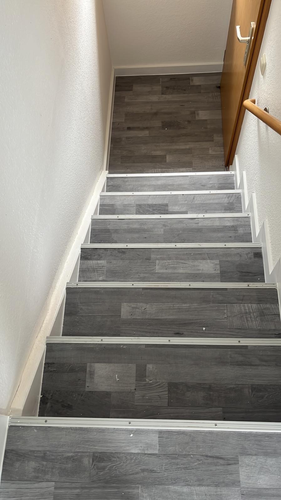 Schody wyłożone panelami w odcieniach szarości z metalowymi listwami, widok z góry. Realizacja z Dębnicy Kaszubskiej.