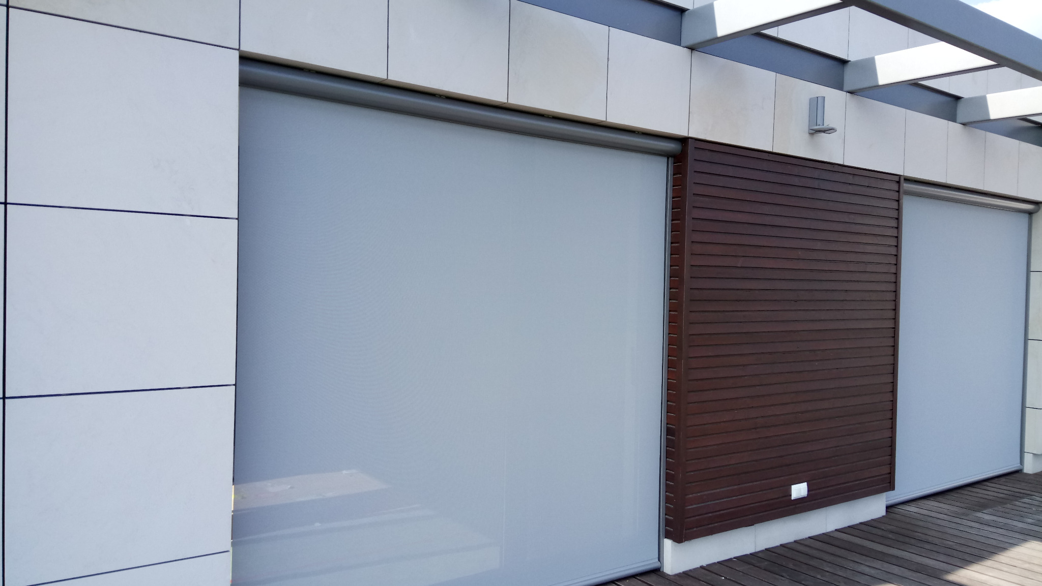 Eleganckie, szare refleksole na tarasie z drewnianą podłogą i panelami. Widoczne detale montażu i faktura materiału. Stonowana kolorystyka, nowoczesny design.