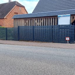 RUSLAN SOKHACH ETERNAL - Nowoczesne, poziome ogrodzenie panelowe w kolorze grafitowym, oddzielające posesję od ulicy. W tle domy z cegły i żółta elewacja, zaparkowane samochody.