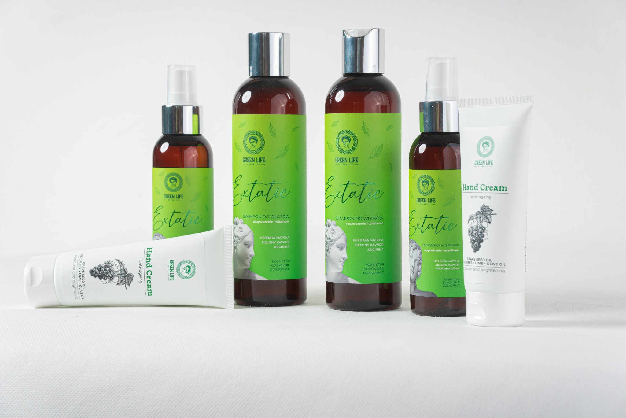 Zestaw kosmetyków Green Life: szampony do włosów, odżywka w sprayu i krem do rąk. Produkty z zielonymi etykietami i srebrnymi nakrętkami na białym tle.