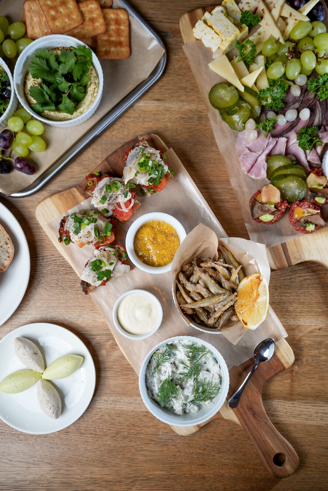 Bogato zastawiony stół z deskami przekąsek: śledzie, sery, wędliny, warzywa, sosy i rybki. Idealne menu na imprezę integracyjną lub event firmowy.