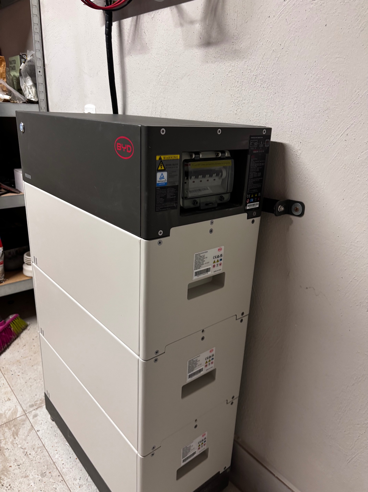 Bateria magazynu energii BYD LVL 15.4, widoczny licznik i naklejki informacyjne, zamontowana przy ścianie w pomieszczeniu gospodarczym.
